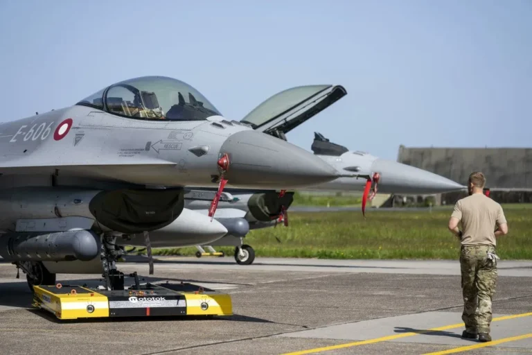 A photo of a Danish F-16 undergoing maintenance on a tarmac.