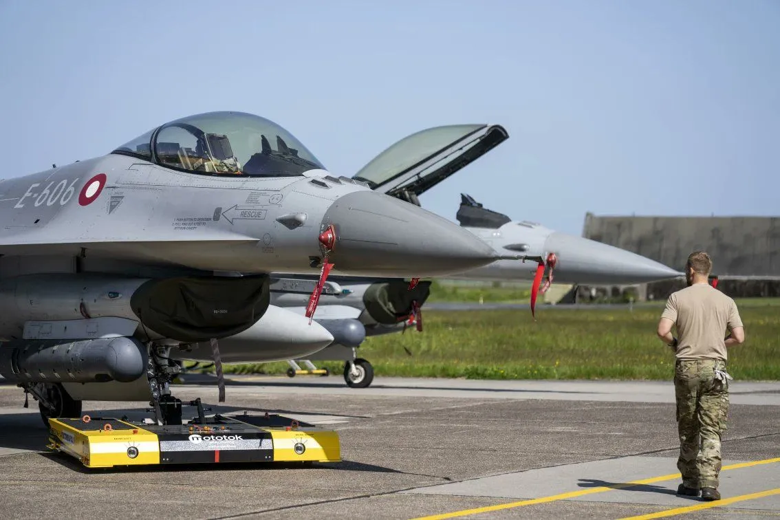A photo of a Danish F-16 undergoing maintenance on a tarmac.