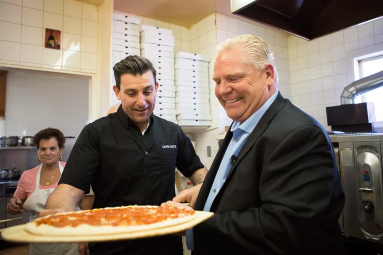 A photo of Doug Ford admiring a pizza indicating How Not to Negotiate: Doug Ford’s Masterclass in Folding Like a Cheap Suit