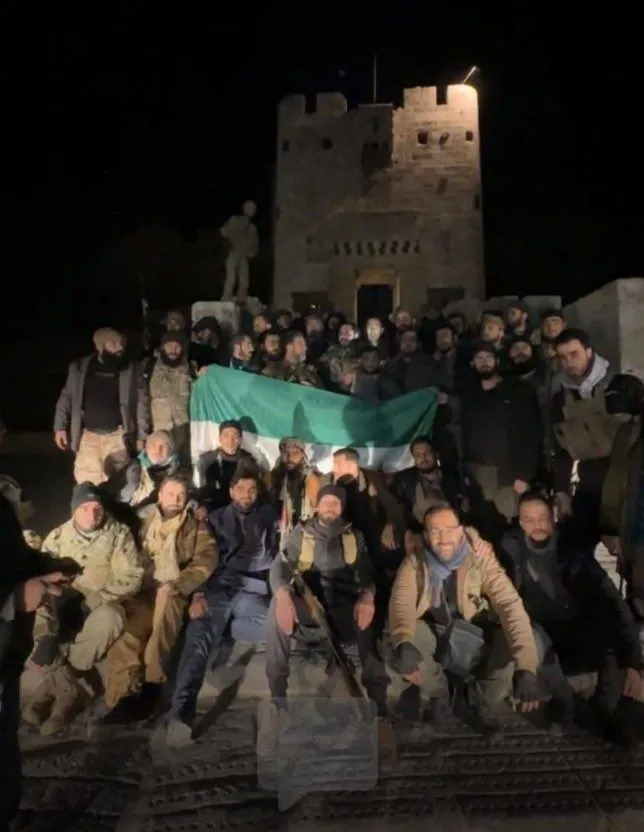 A photo of SDF and HTS rebels posing with the Free Syrian Army Flag in Aleppo, Syria. 