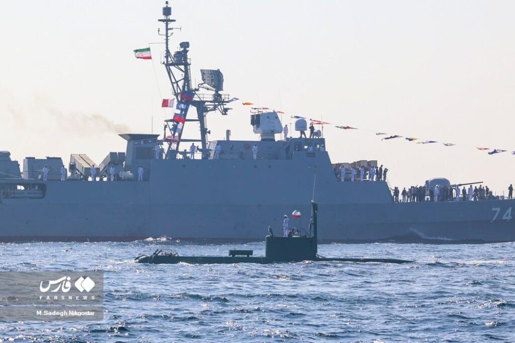 An Iranian Ghadir Class Submarine juxtaposed with a frigate on Navy Day 1401 illustrating the platform's small size