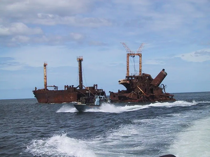 A LTTE Sea Tiger fast attack fiberglass boat passing a Sri Lankan freighter sunken by the Sea Tigers just north of the village of Mullaitivu, North-eastern Sri Lanka.  Photo taken by Isak Berntsen, in Mullaitivu, Sri Lanka, 2003. A LTTE Sea Tiger fast attack fiberglass boat passing a Sri Lankan freighter sunken by the Sea Tigers just north of the village of Mullaitivu, North-eastern Sri Lanka.