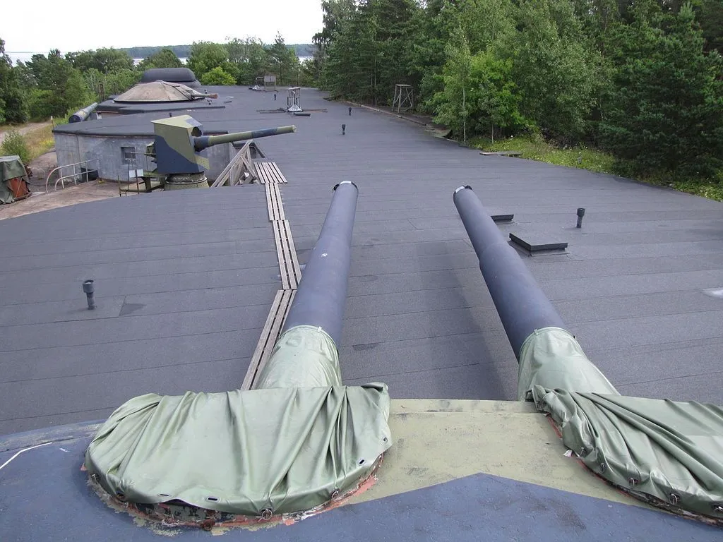 Coastal artillery exhibition in Kuivasaari island. Photo taken from the roof of a 305 mm double turret, 152 mm Canet gun in original condition next, rebarreled Canet with 152 mm Tampella barrel under cupola, command point last. The position is originally built for 254 mm Durlacher guns in single mountings; one such gun is in the fourth position behind the photographer. Credit alternativefinland.com